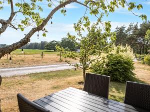 a picnic table with chairs and a view of a field at Chalet Ringsegård Höjden - HAL045 by Interhome in Falkenberg