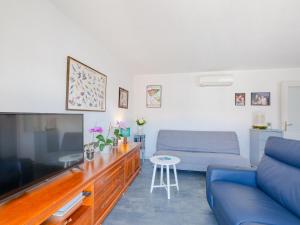 uma sala de estar com um sofá azul e uma televisão grande em Apartment Royal Marine-4 by Interhome em Fréjus