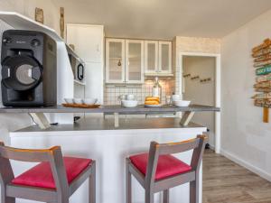 a kitchen with a counter with two chairs and a microwave at Apartment Primavéra-8 by Interhome in Lacanau-Océan