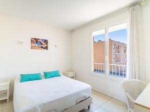 a white bedroom with a bed and a window at Apartment Les Ilaires by Interhome in Le Lavandou