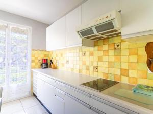 une cuisine avec des placards blancs et du carrelage jaune dans l'établissement Apartment Les Ilaires by Interhome, au Lavandou