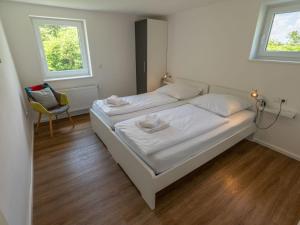 a bedroom with two beds and a chair and two windows at Holiday Home Schwarzwald by Interhome in Dittishausen