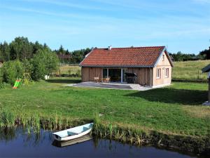 a small house with a boat in the water at Holiday Home Zagroda nad Krutynią by Interhome in Spychowo