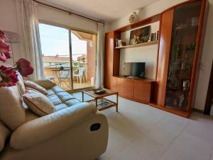 a living room with a couch and a large window at Apartamentos El Dorado in Miami Platja