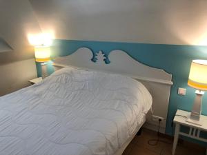 - une chambre avec un lit blanc aux murs bleus et 2 lampes dans l'établissement 2 Pièces Premium avec terrasse vue mer Résidence Pierre et Vacances, à Sainte-Luce