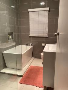 a bathroom with a tub and a sink and a toilet at Charming & Cozy 2BR Cottage in Blacktown