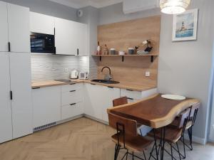 eine Küche mit einem Holztisch und weißen Schränken in der Unterkunft Uroczy Apartament Happy 28 tuż przy plaży. in Sianożęty