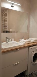 ein Badezimmer mit einem Waschbecken und einer Waschmaschine in der Unterkunft Uroczy Apartament Happy 28 tuż przy plaży. in Sianożęty