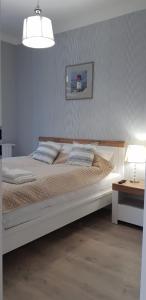 ein Schlafzimmer mit einem großen weißen Bett und einem Tisch in der Unterkunft Uroczy Apartament Happy 28 tuż przy plaży. in Sianożęty