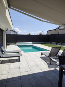 a swimming pool with two chairs and a table at Villa Almaé - Maison neuve proche plages avec piscine chauffée in Ambon