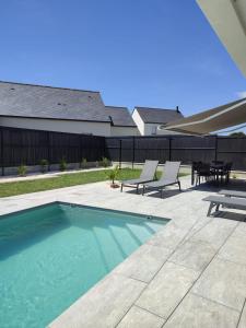 einen Pool mit 2 Stühlen und einem Tisch in der Unterkunft Villa Almaé - Maison neuve proche plages avec piscine chauffée in Ambon