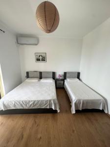 Habitación con 2 camas, paredes blancas y suelo de madera. en XHEKO ROOMS, en Dhërmi