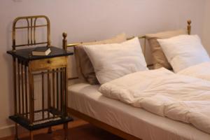 a bed with white sheets and a night stand next to it at Oreg Parokia Guesthause in Meggyeskovácsi