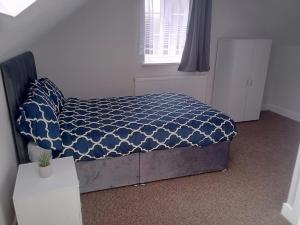 a bedroom with a bed with a blue comforter and a window at Modern Spacious 4 Bed House-with Private Parking in Birmingham 