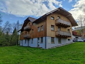 a large wooden house with balconies on a green field at Apartmán Kovárna in Prášily