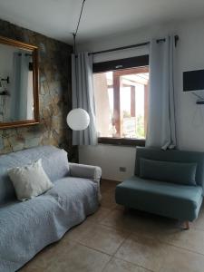 La Finestra su Stintino في ستينتينو: غرفة معيشة بها أريكة وكرسي ونافذة