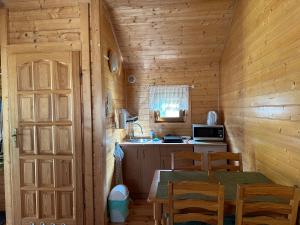 a kitchen with a table in a wooden cabin at Jantar Rodzinne Domki in Bobolin