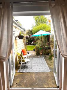 a patio with a table and an umbrella and a chair at Cosy 19th century two bedroomed home with continental Breakfast in Bath