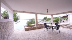 un patio con mesa y sillas y vistas al agua en SOL ET PAX, en Veliki Drvenik