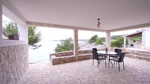 eine Terrasse mit Tisch und Stühlen und Blick auf das Wasser in der Unterkunft SOL ET PAX in Drvenik Veli