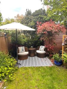 a patio with two chairs and an umbrella at Cosy 19th century two bedroomed home with continental Breakfast in Bath