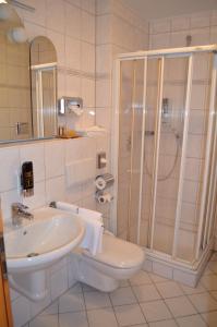 ein weißes Bad mit einer Dusche und einem Waschbecken in der Unterkunft Wagners Fränkischer Hof in Altenkunstadt