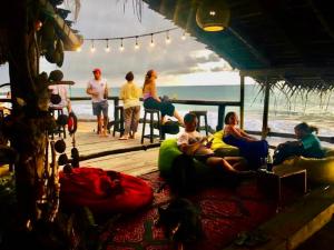 un grupo de personas sentadas en una terraza cerca de la playa en Backpack Beach Hostel & Reggae Bar en Galle
