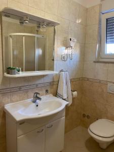 une salle de bain avec un lavabo, des toilettes et un miroir dans l'établissement Apartments Marija, à Biograd na Moru