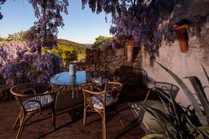 a table and chairs on a patio with purple flowers at La Vieille Maison - Halte Gourmande in Durfort-et-Saint-Martin-de-Sossenac