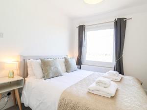 a bedroom with a white bed with towels on it at Long View in Southwold