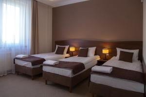 een hotelkamer met 2 bedden en 2 lampen bij Camelot in Sandomierz
