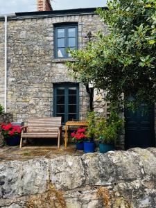 a wooden bench sitting in front of a stone house at Nightingale Cottage in Llantwit Major