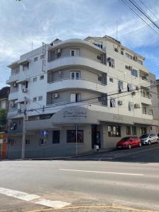 a large white building with cars parked in front of it at Hotel Dom Rafael Express in Santa Maria