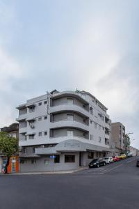 un gran edificio blanco con coches estacionados frente a él en Hotel Dom Rafael Express en Santa Maria