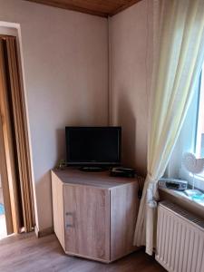 TV en un soporte de madera en una habitación con ventana en Uns lütt Hus, en Krakow am See