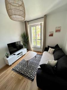 Bel appartement Porte d’Italie في لو كرملين-بيستر: غرفة معيشة بها أريكة وتلفزيون