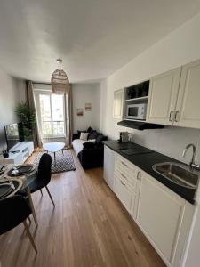 Bel appartement Porte d’Italie في لو كرملين-بيستر: مطبخ وغرفة معيشة مع أريكة وطاولة