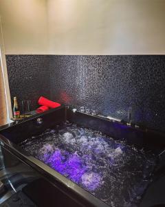bagno con vasca nera e acqua viola di Suite de prestige avec spa & cinéma a Ivry-sur-Seine