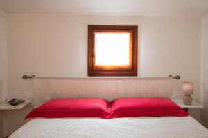 a bedroom with a bed with red pillows and a window at Casa Olbiamare by Wonderful Italy in Olbia