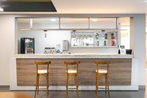 a bar with three stools in front of a counter at Hotel Dom Rafael Premium in Santa Maria
