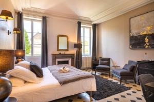 a bedroom with a large bed and a fireplace at Hôtel Le Clos du Colombier 1817 Vignes & Spa in Pommard