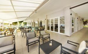 un patio con tavoli, sedie e tavolo da trucco di Olive Family Suites - Hotel & Resort Adria Ankaran ad Ancarano