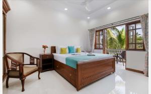 a bedroom with a bed and a chair and a window at Anthy’s à la Campagne in Benaulim +16 photos