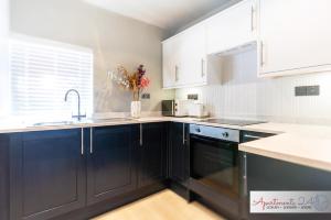 a kitchen with black cabinets and a sink at Beautiful Apartment In London in Hounslow