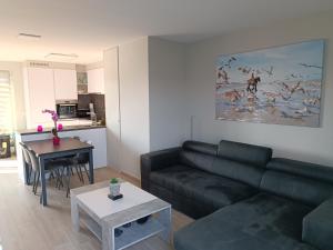 a living room with a black couch and a table at Koksijde Penthouse in Koksijde