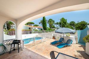 a patio with chairs and an umbrella and a pool at BeGuest Vale de Lobo 932 Villa in Almancil