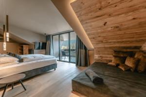 a bedroom with a bed and a table and a large window at Hotel Alpenrose in Carezza al Lago