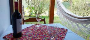 a bottle of wine and two glasses on a table at Pousada Asa do Vento in São Luiz do Paraitinga