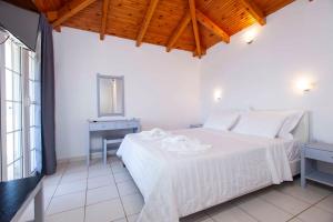 ein weißes Schlafzimmer mit einem weißen Bett und einem Fenster in der Unterkunft Kontogoni Rooms in Elafonisos