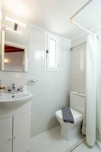 een witte badkamer met een toilet en een wastafel bij Kontogoni Rooms in Elafonisos